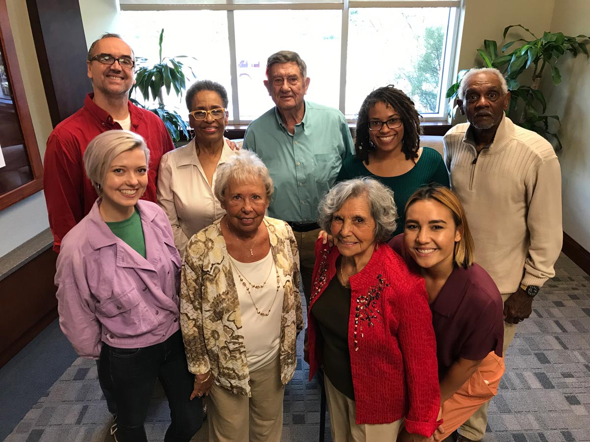 Group of seniors and family caregivers smile and pose